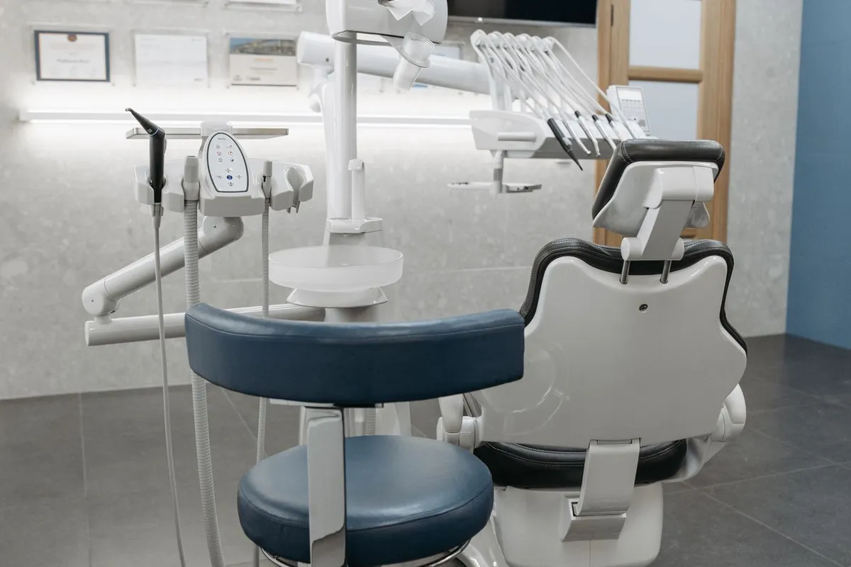 A dental surgery ready for the next patient: the chair and instrument arm under the operating light, with the practitioner's stool alongside.